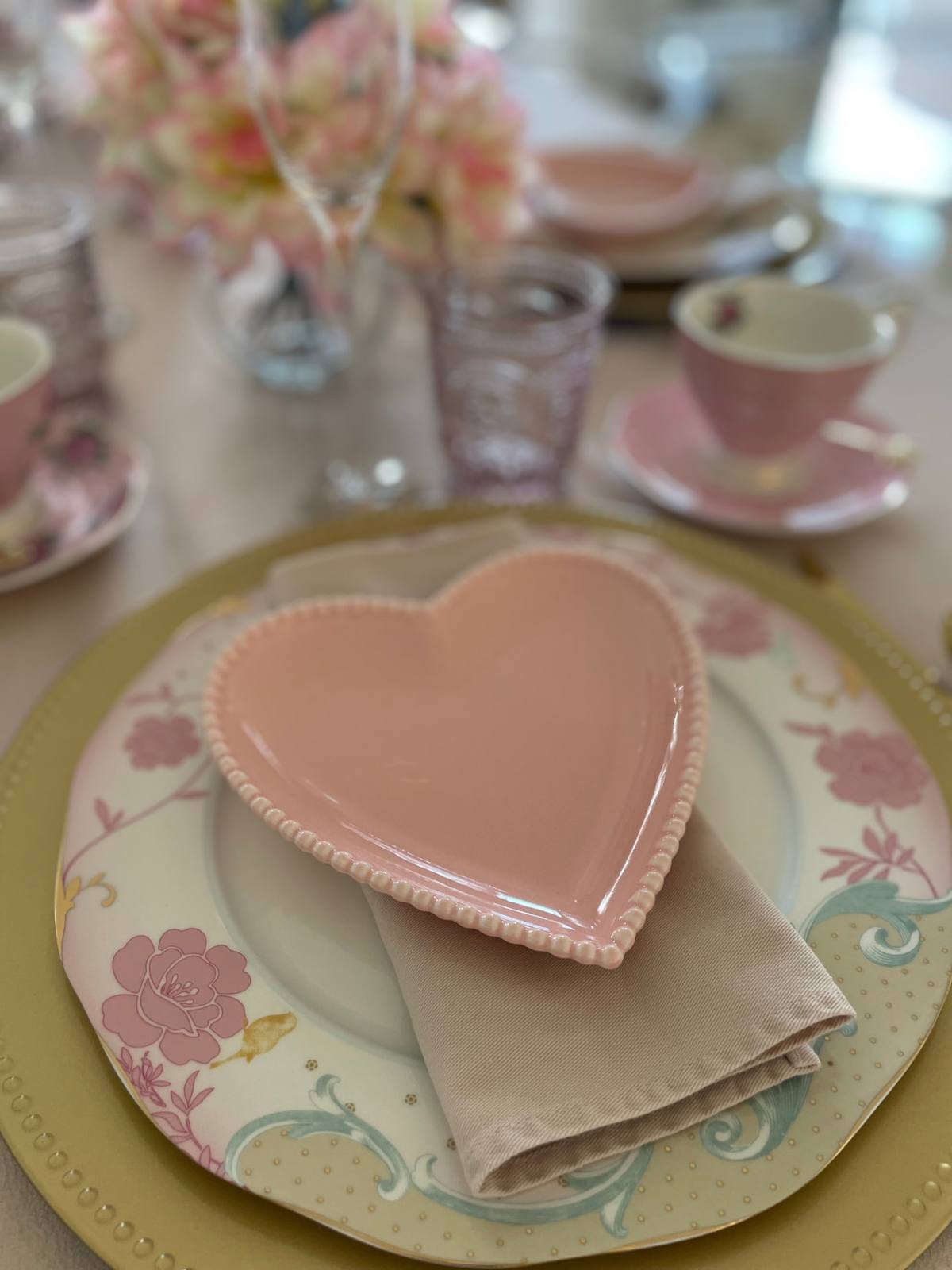 A pink heart-shaped plate on a floral charger