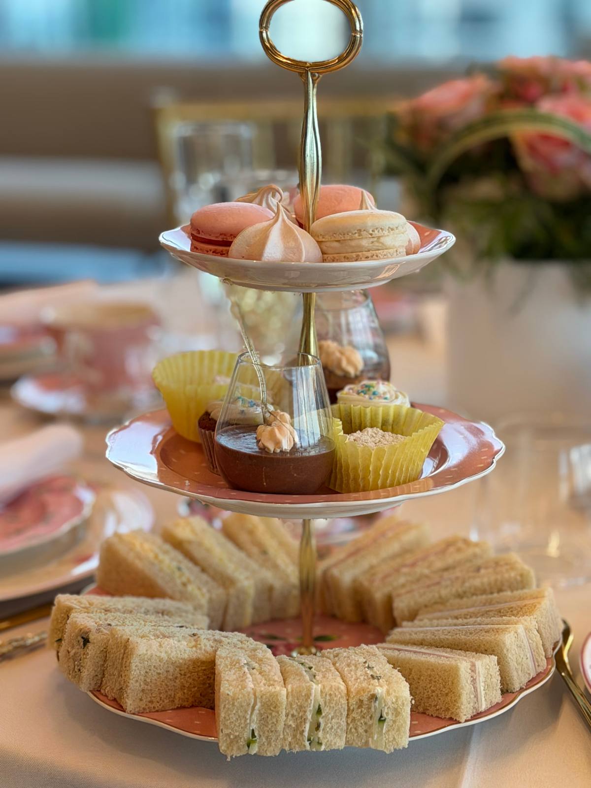 A tiered stand of macarons, cupcakes and finger sandwiches