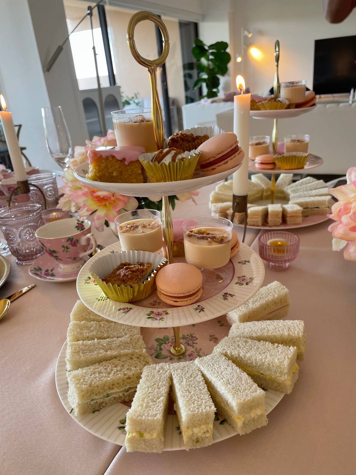 A tiered stand with macarons, sandwiches and vintage teacups