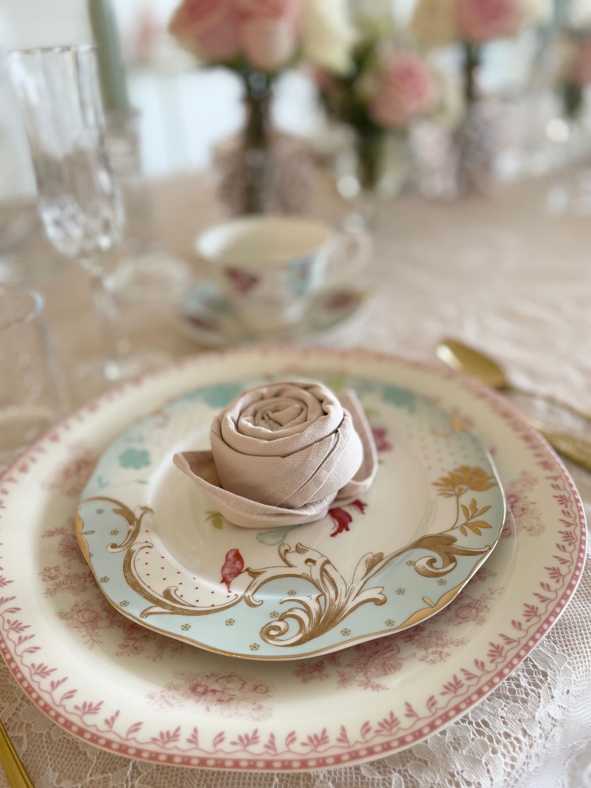 A napkin folded into a rose on a decorative floral plate