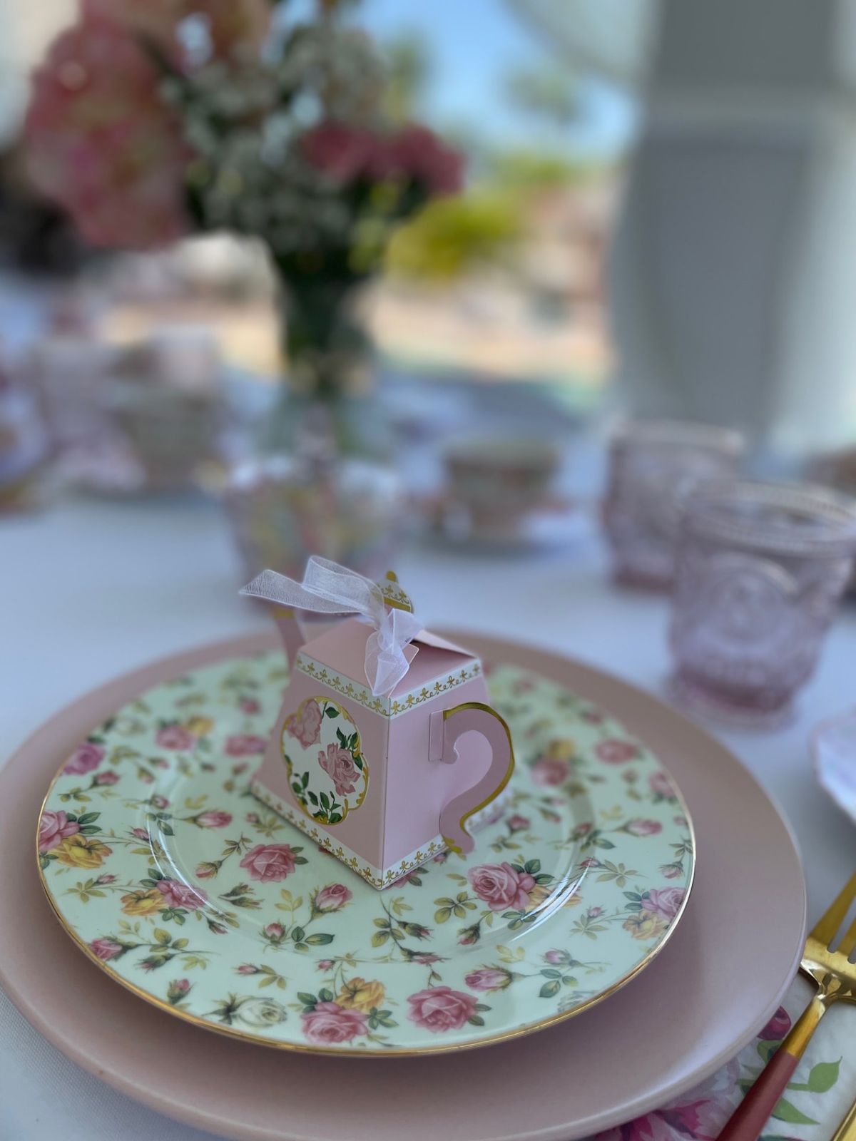 A small pink teapot-shaped favour box on a floral plate