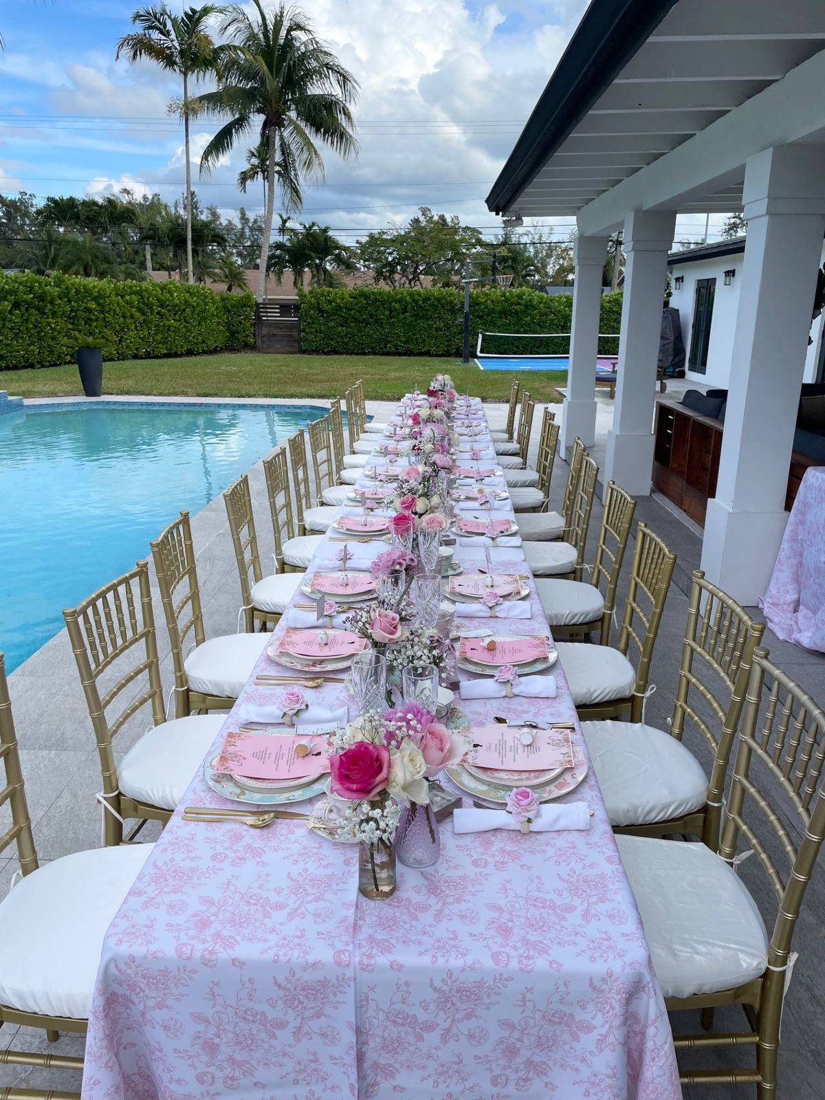 A long poolside table styled for an outdoor afternoon tea