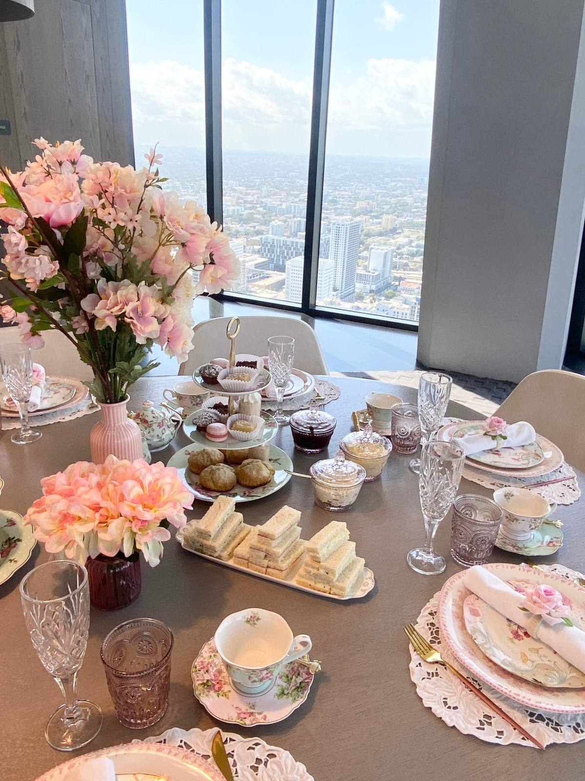 An afternoon tea spread set against floor-to-ceiling city windows