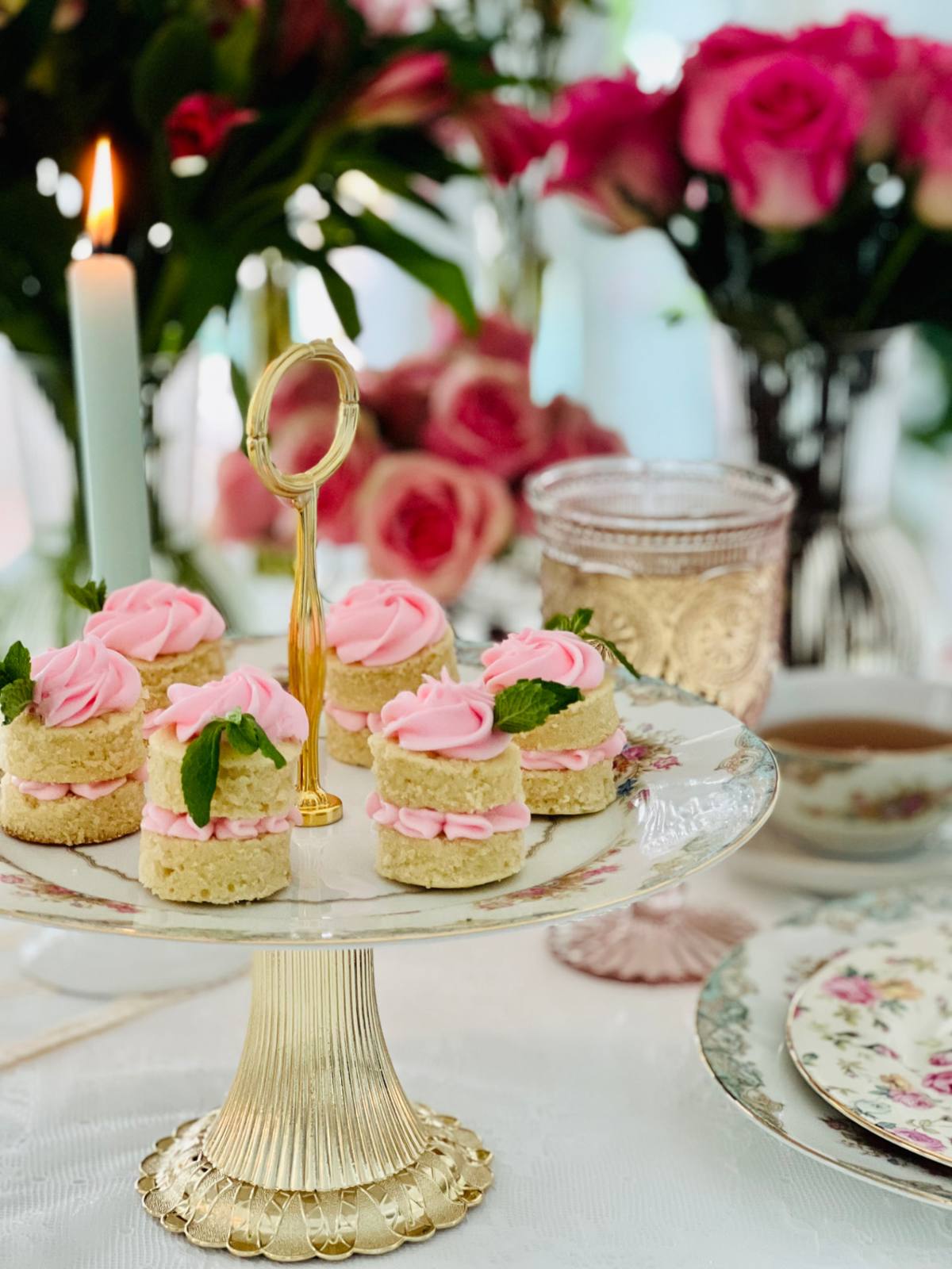 Mini layer cakes with pink buttercream on a gold cake stand