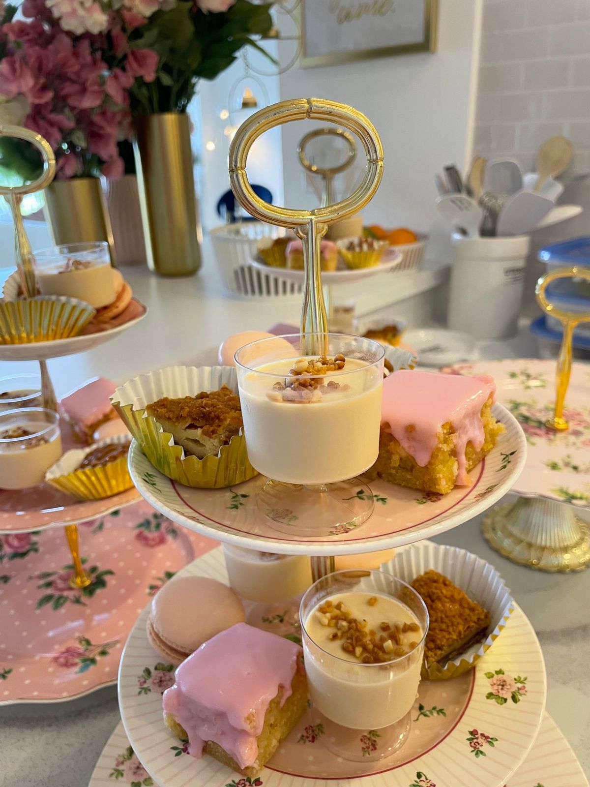 Top tiers of a tea stand with pink-frosted cakes and macarons