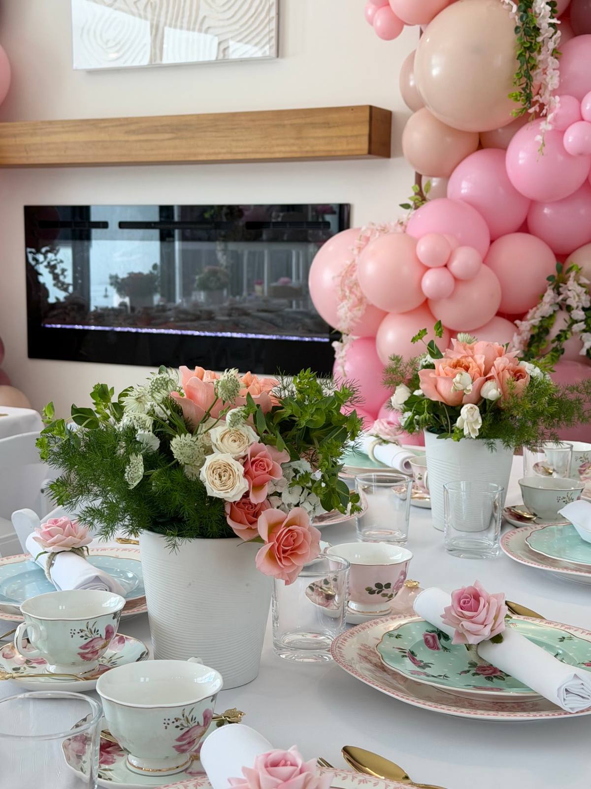 Blush florals and balloons framing a residential tea setup