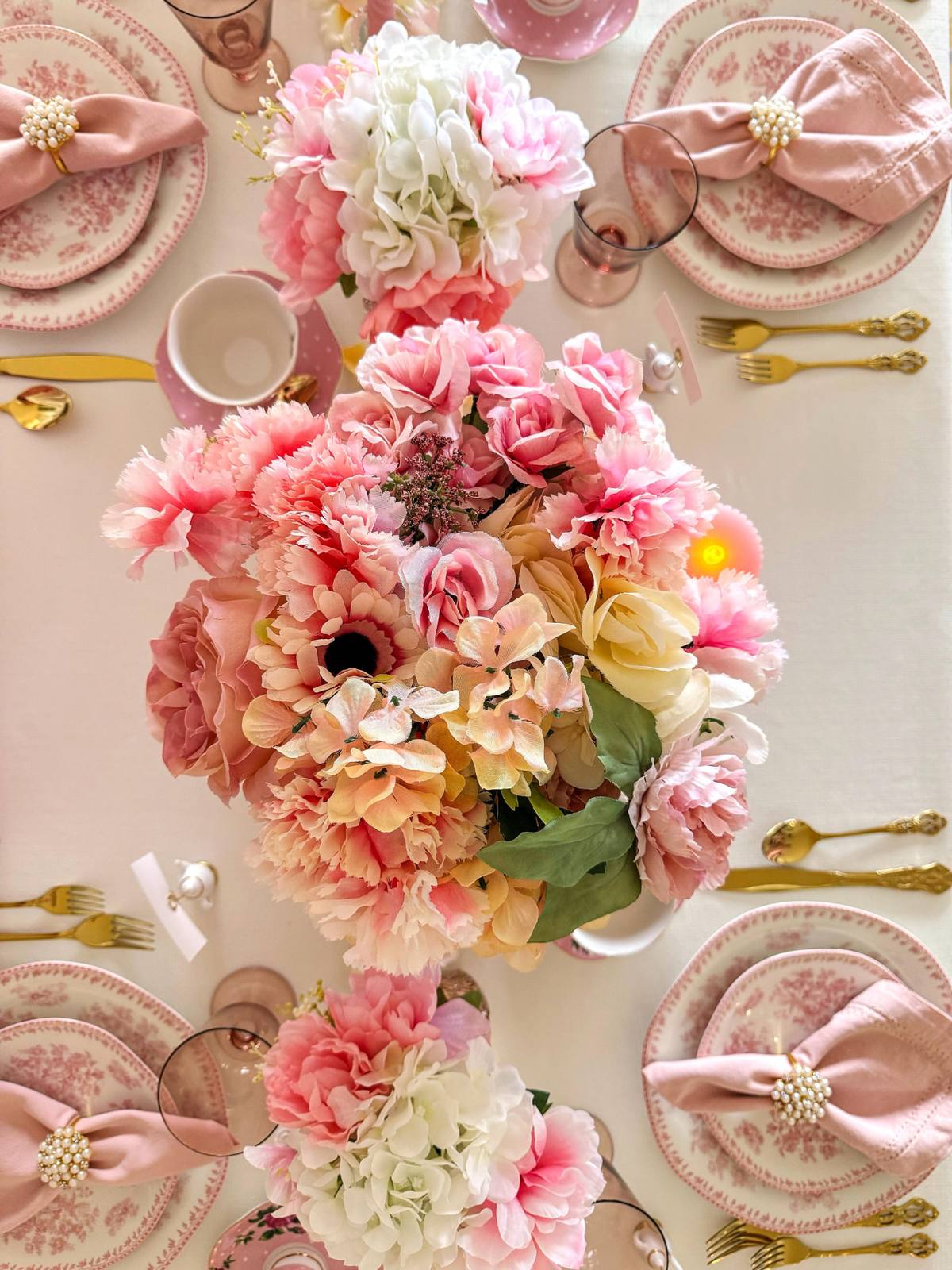 A lush pink and blush floral centrepiece on a styled tea table