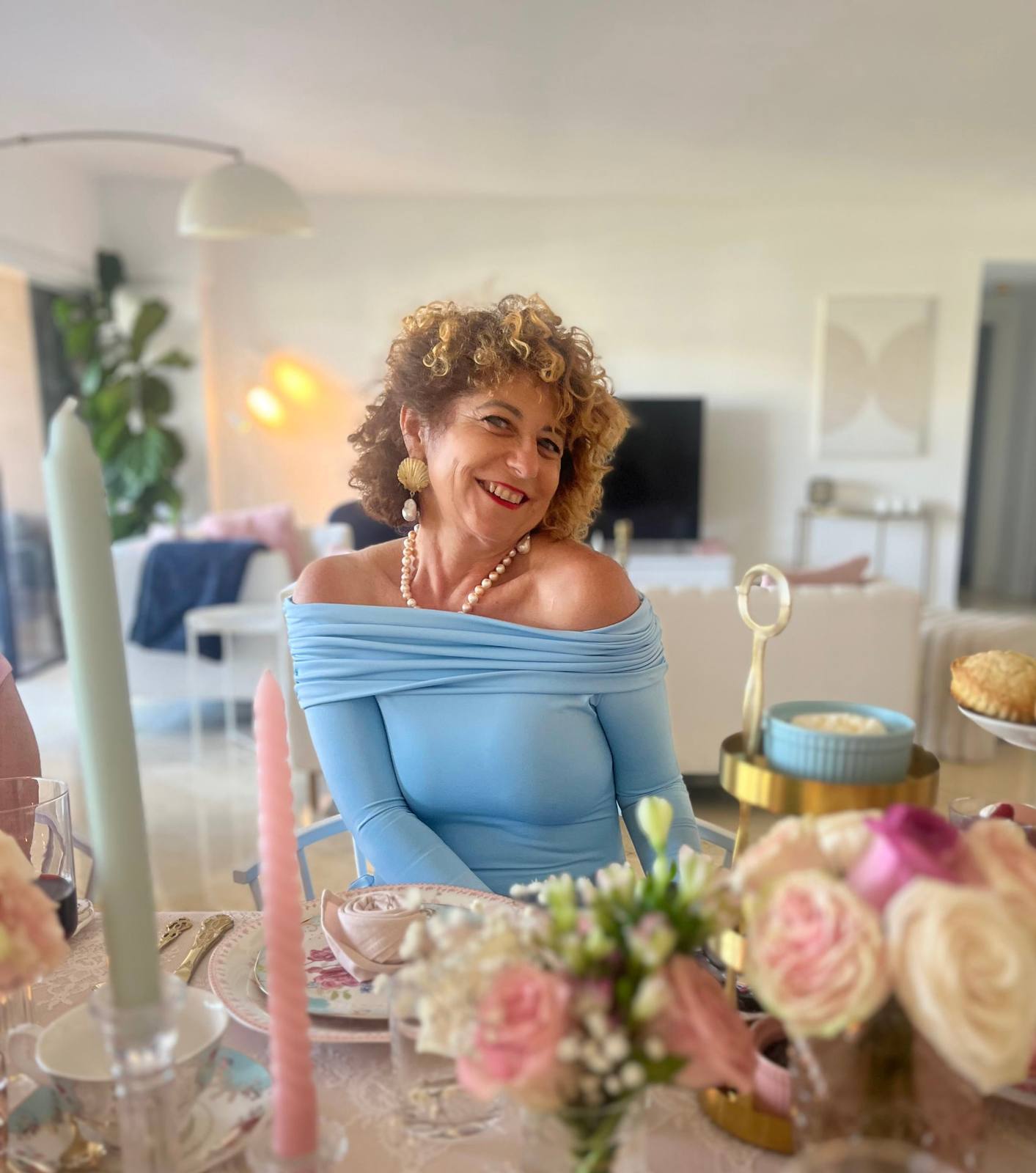 A guest smiling at a styled afternoon tea table in a bright residence