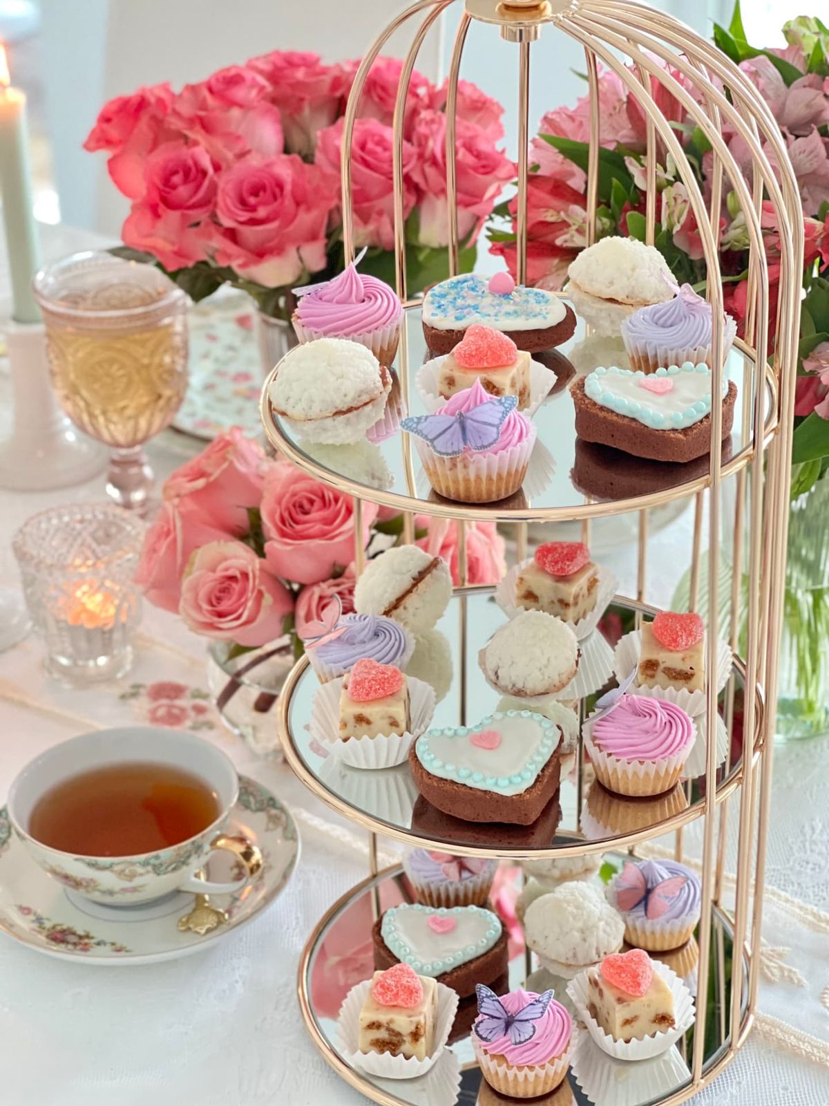 A birdcage-style tiered stand with heart cookies and butterfly cupcakes